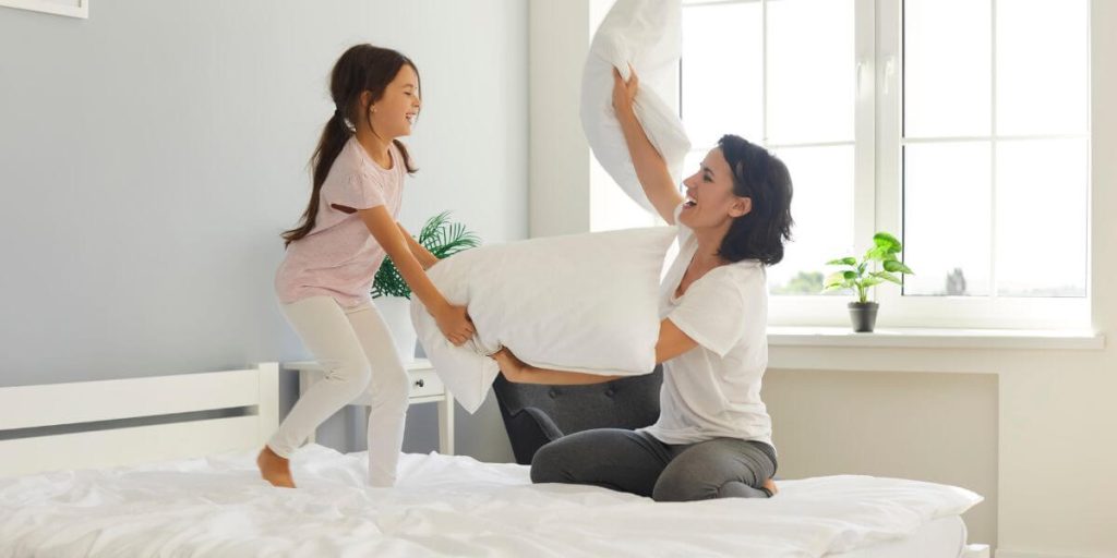 Mother and daughter having a pillow fight on a mattress